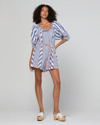 A woman modeling a blue, white, and red striped romper with puff sleeves and a tie waist