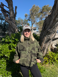 a green camouflage fleece jacket, by frankie with black leggings.