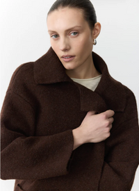 Woman wearing a brown coat by little lies
