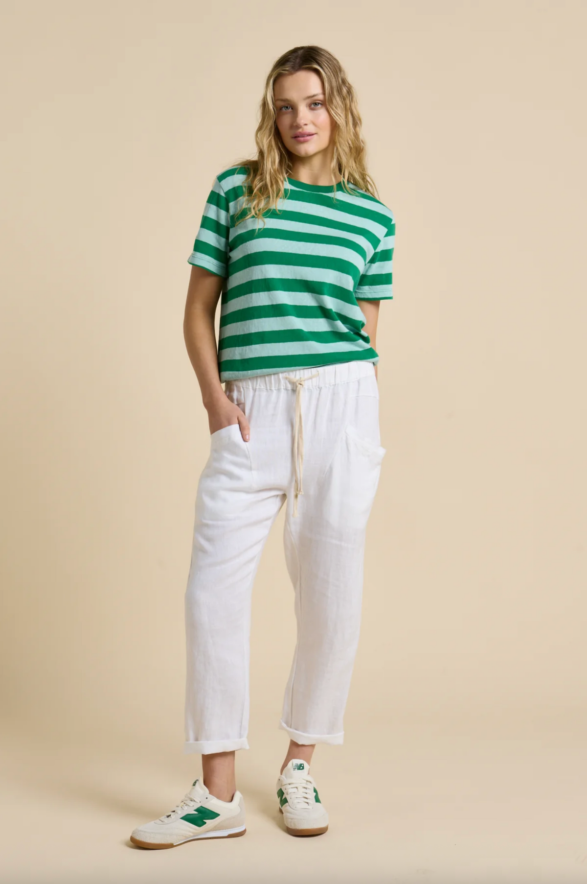 Woman wearing a green and white striped shirt with white pants 